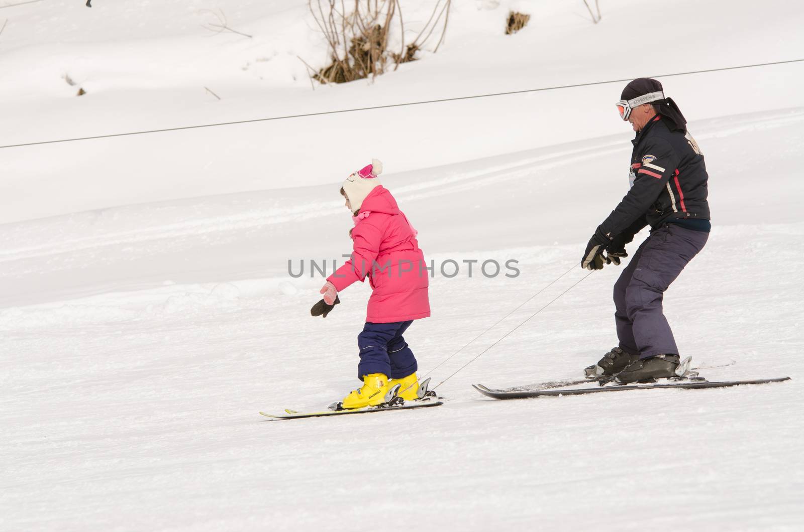 Dombay, Russia - February 7, 2015: A man learns to ski teenage girl on a snow-covered slope ski resort Dombai