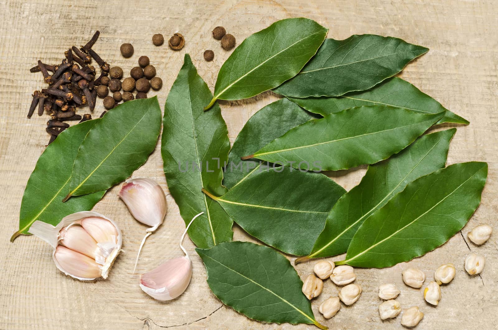 Bay leaf and pepper with cloves, lying on a wooden background .