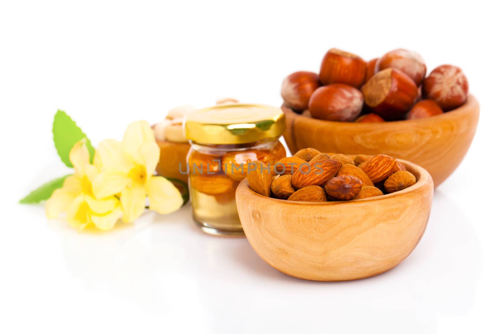 Hazelnuts in a wooden bowl on white background