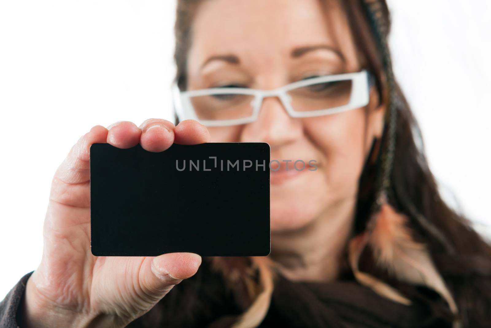Brunette woman holding up a blank credit card business card shoppers club card or gift card of some sort with copyspace. Shallow depth of field.