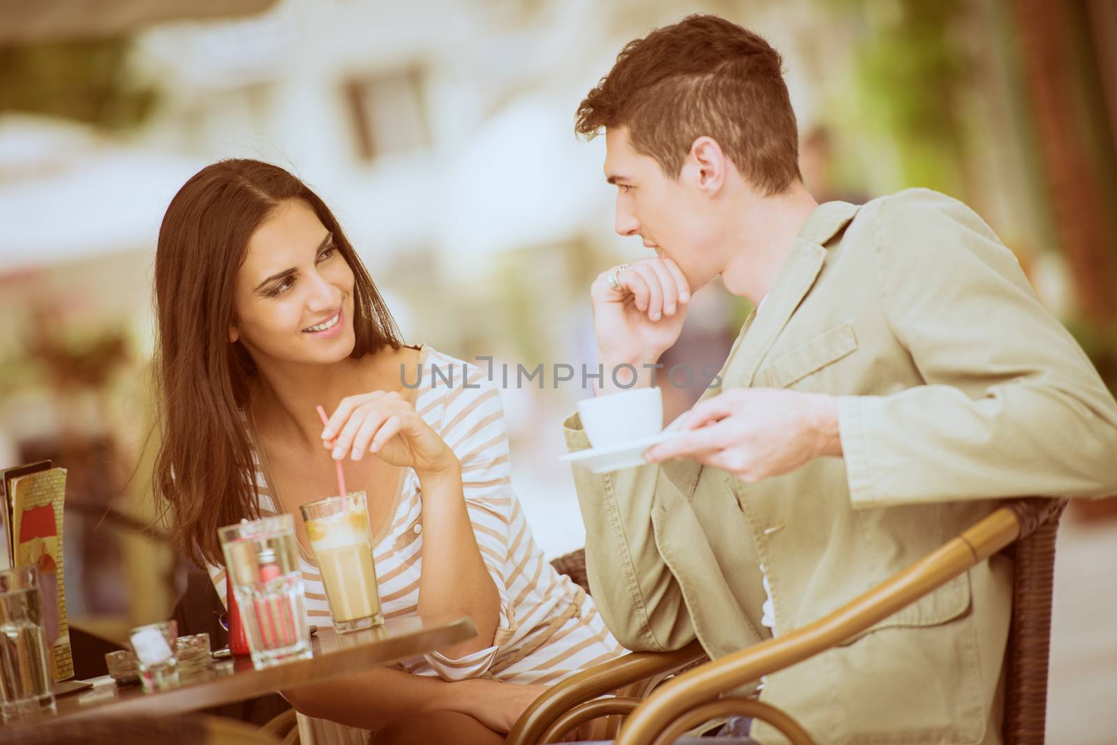 Young couple in garden cafe flirts and enjoys the coffee.