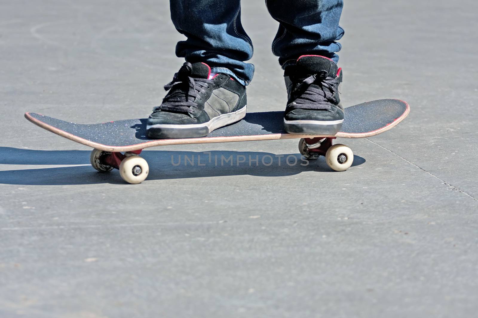 Close up of a skateboarders feet while skating on concrete at the skate park. 