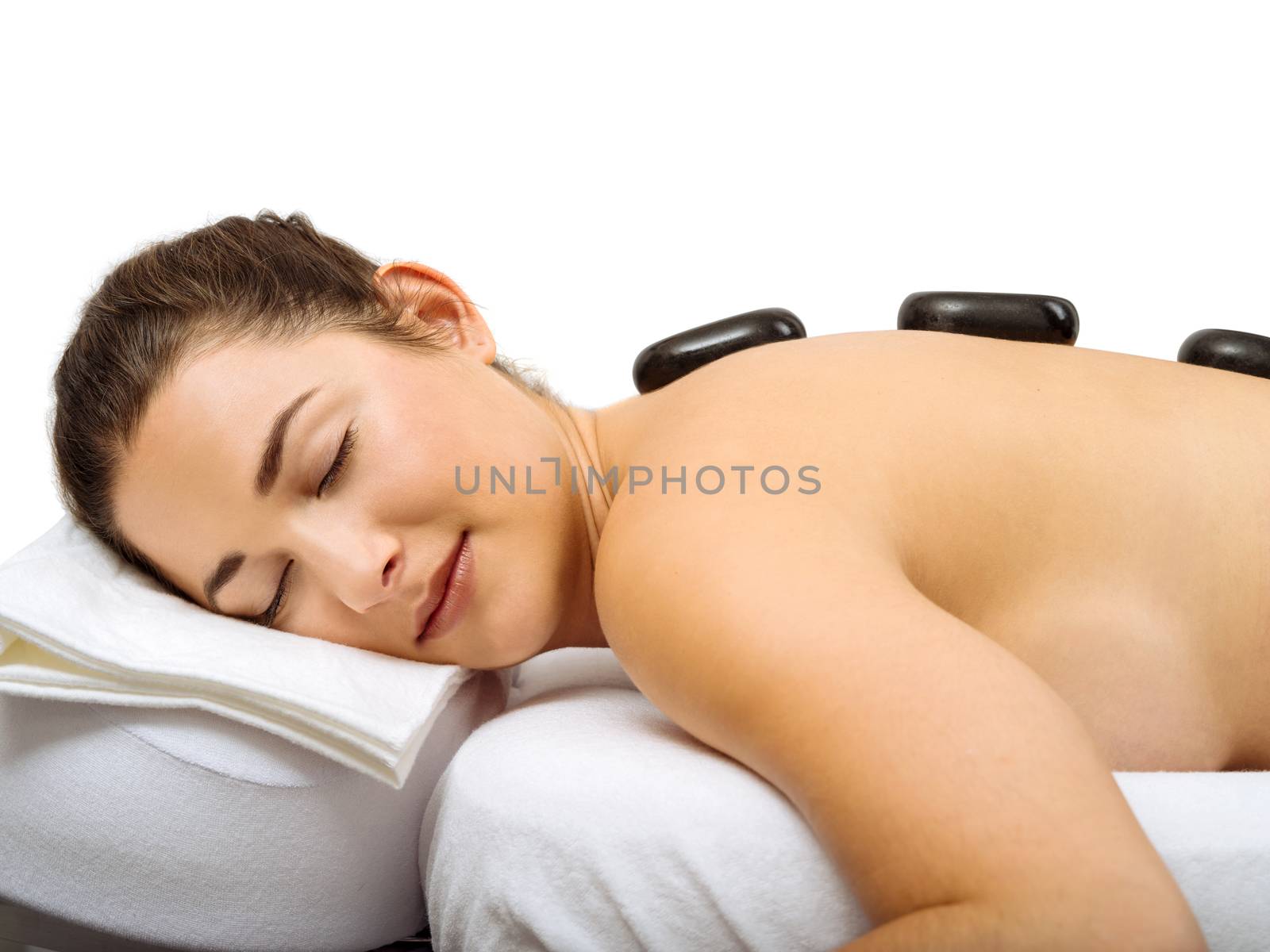 Photo of a young woman lying in a spa having a hot stone treatment.
