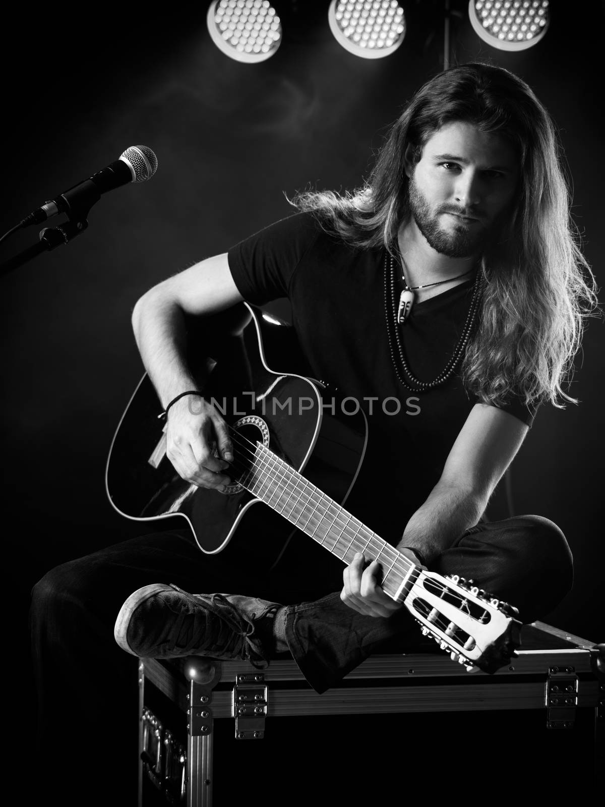 Man playing acoustic guitar on stage by sumners