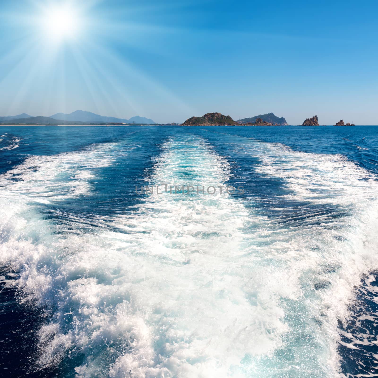 Waves on blue sea behind the speed boat water with bright sun shining on the sky