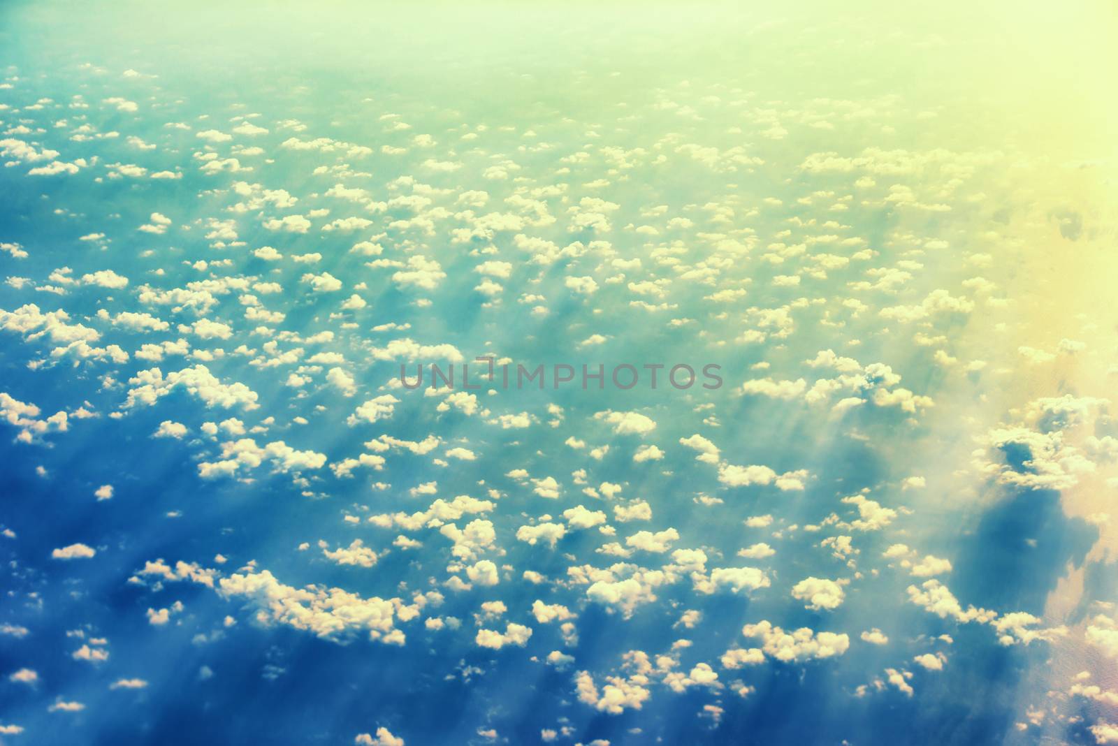 View from a plane to sunset on the sky with sunrays. Fluffy clouds background