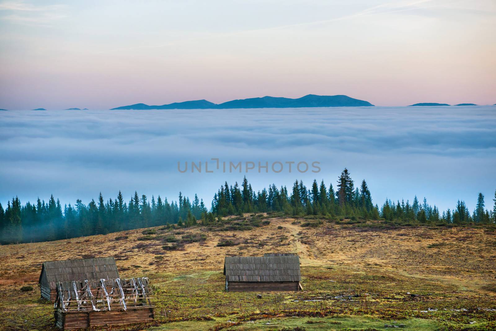 Old house in front of beautiful nature with clouds ocean, field of grass and mountains