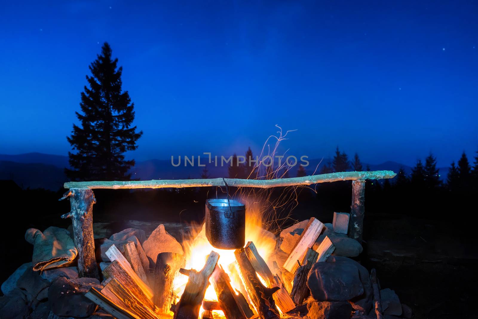 Cooking food in the pot on fire under blue night sky with many stars