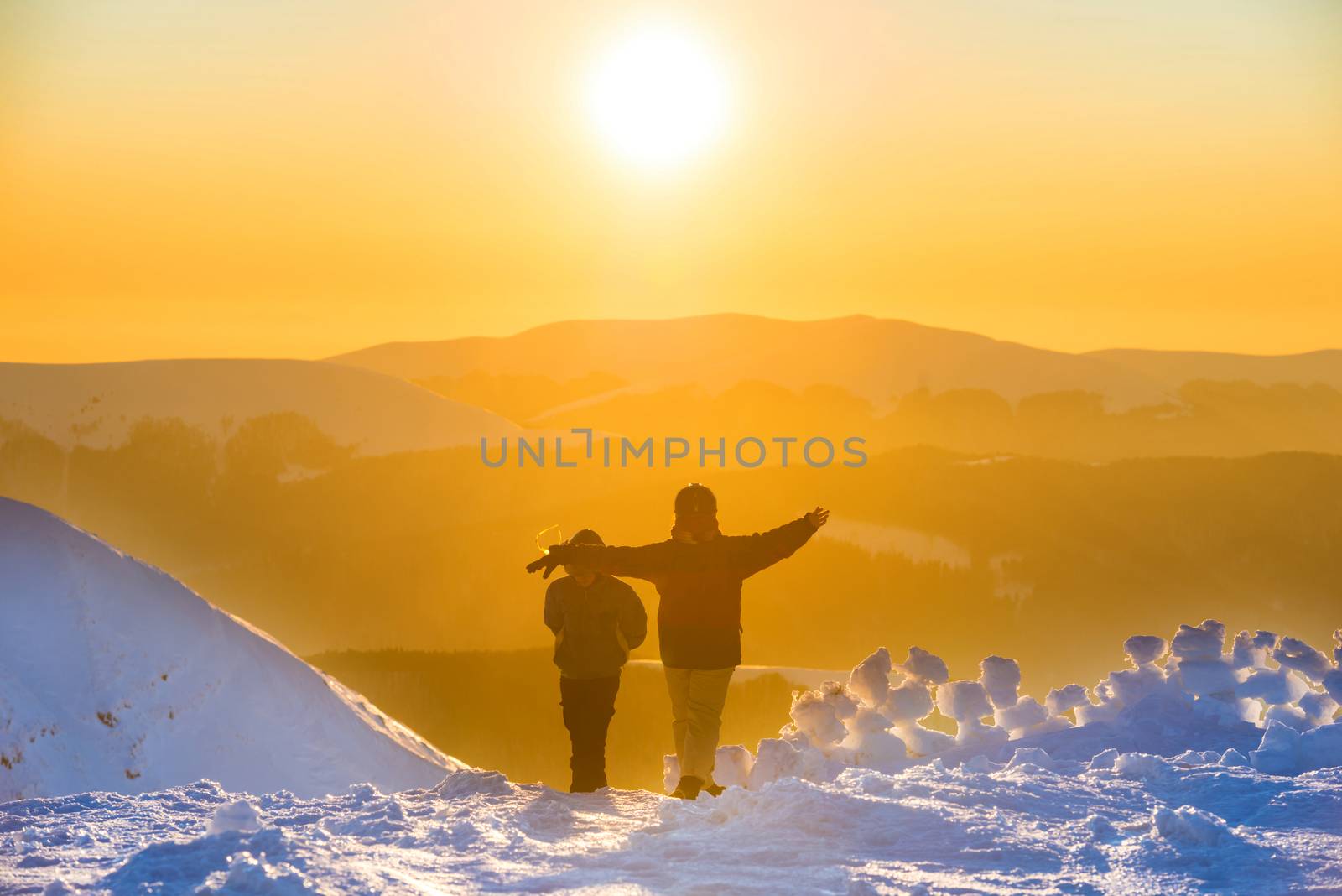 People walking at sunset in winter mountains by vapi