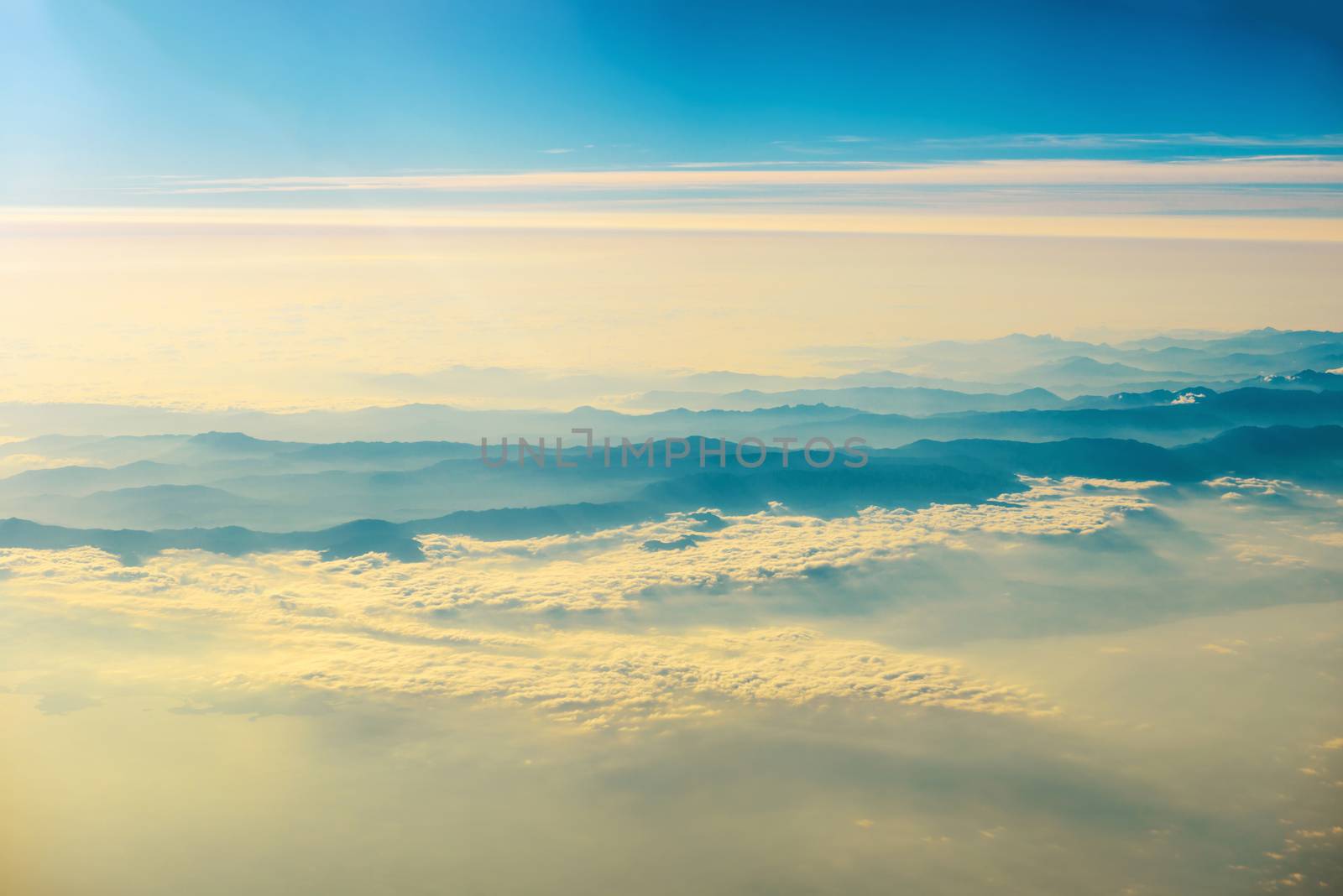 View from a plane to sunset on the sky with sunrays. Fluffy clouds background