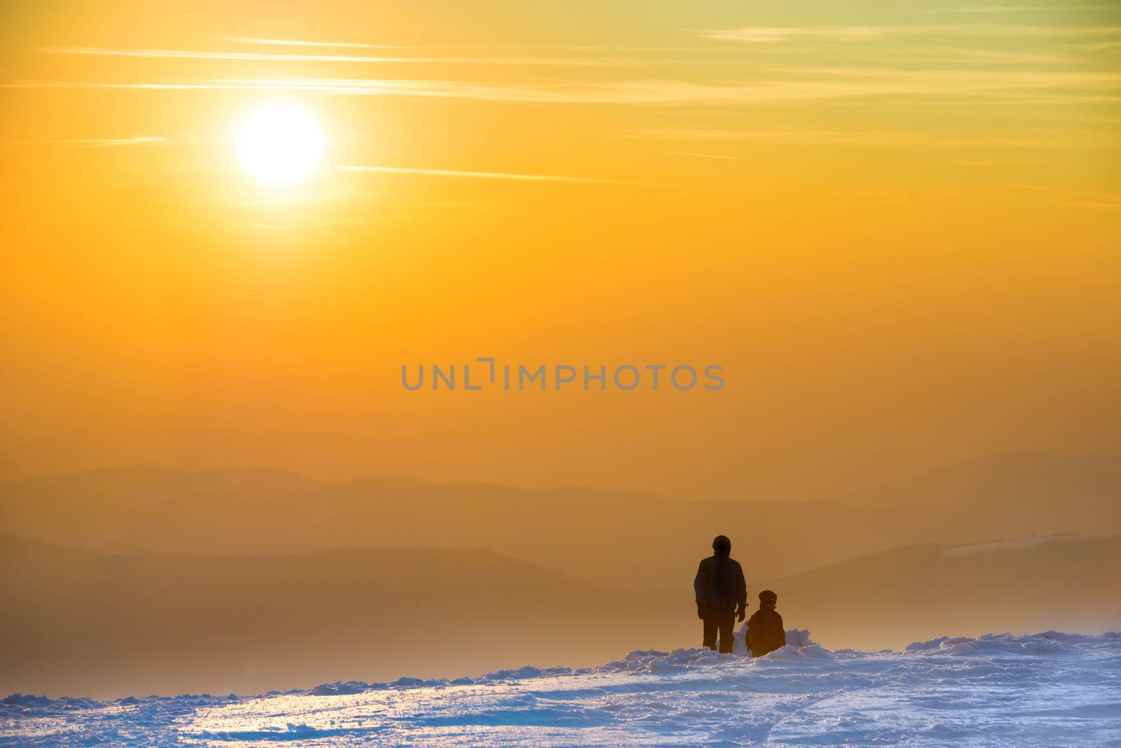 People looking at sunset in winter mountains covered with snow