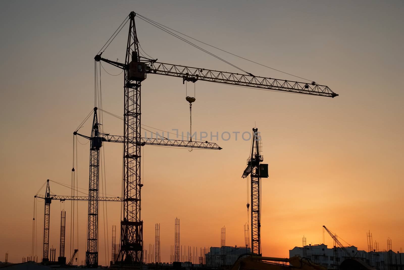 Industrial landscape with silhouettes of cranes on the sunset background