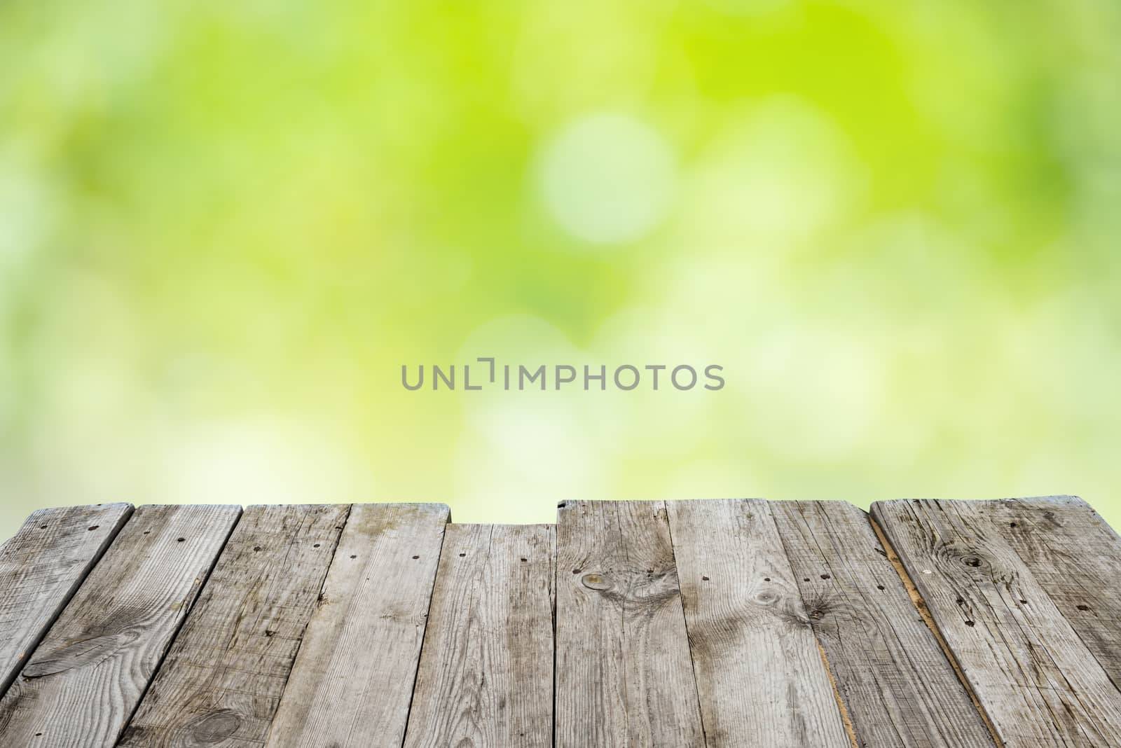 Empty wooden table with foliage bokeh by vapi