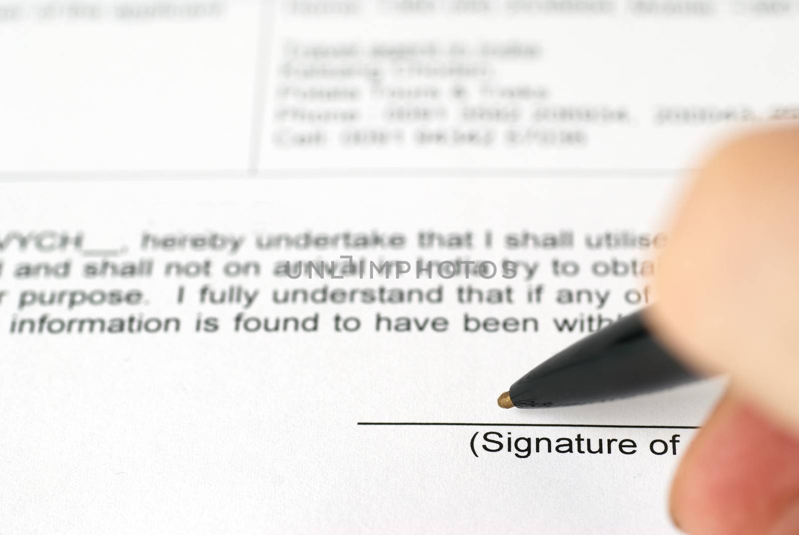 Businessman's hand with pen signing contract. Selective focus on top of pen.