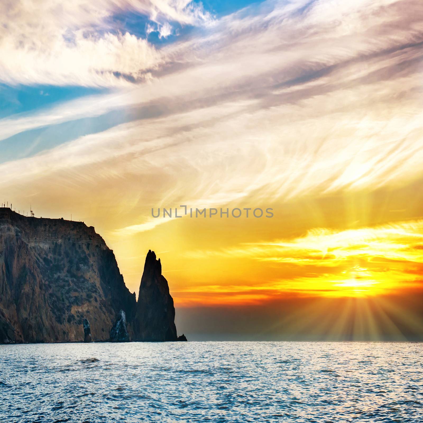 Sea landscape with sunset over rocks and dramatic sky