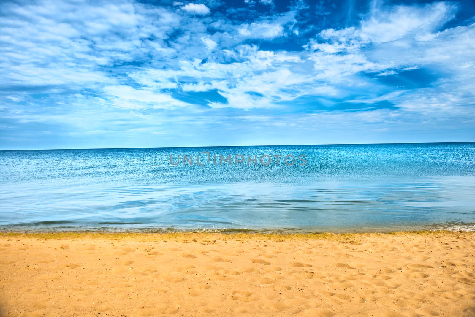 Beautiful summer sea abstract background. Golden sand beach with blue ocean and cloudscape and sunset