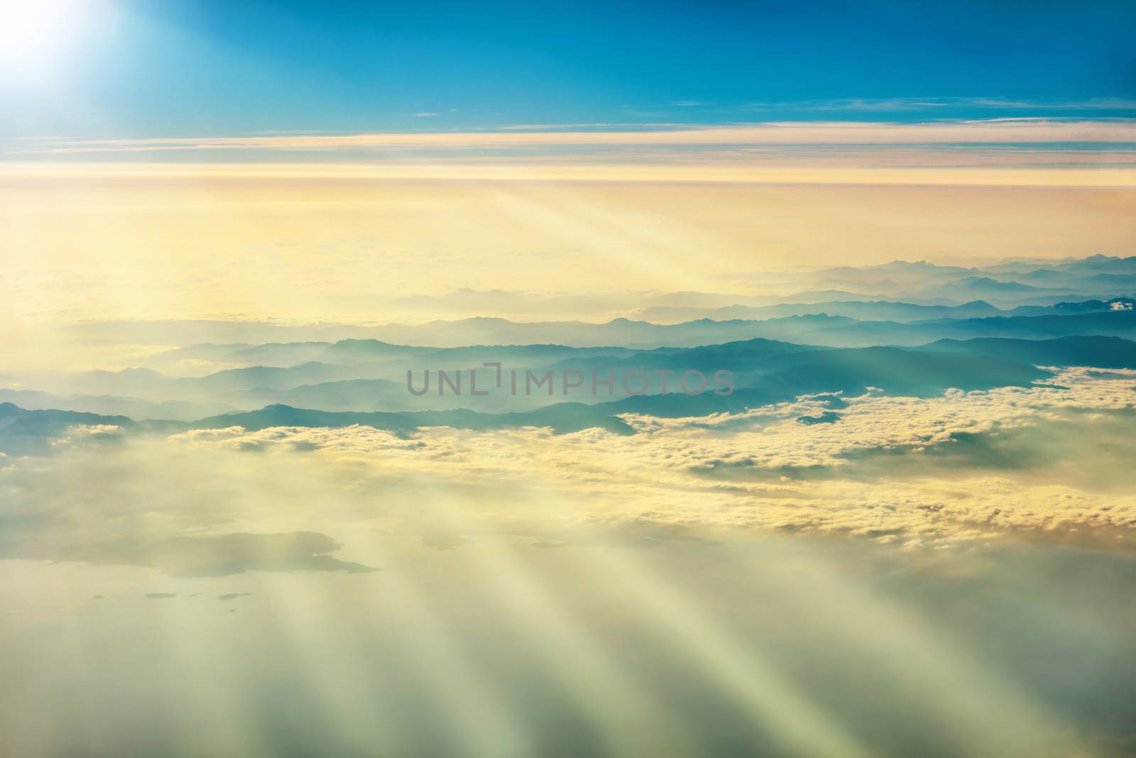 View from a plane to sunset on the sky with sunrays. Sunbeams shining through clouds