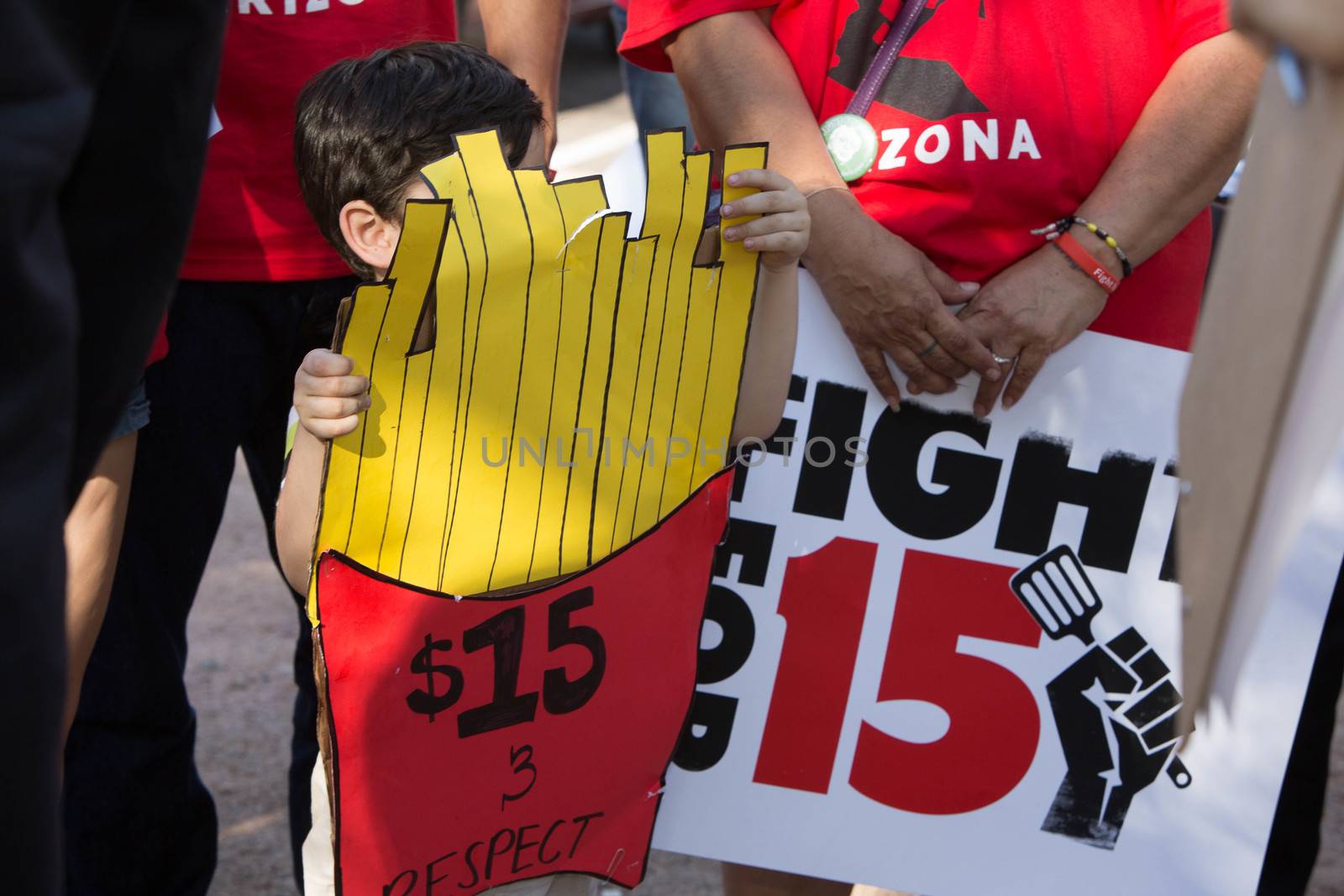 UNITED STATES, Phoenix: A child holds a sign in the shape of a cone of fries reading ' & respect' as hundreds of workers and supports took to the streets in Phoenix, Arizona on April 14, 2016 to call for a national minimum wage increase to  an hour. 