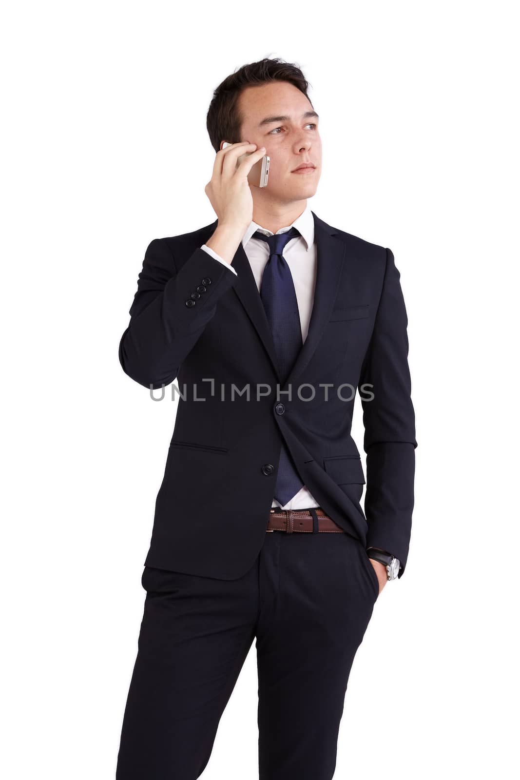 A young caucasian male businessman looking thoughtful holding a mobile phone looking away from camera.
