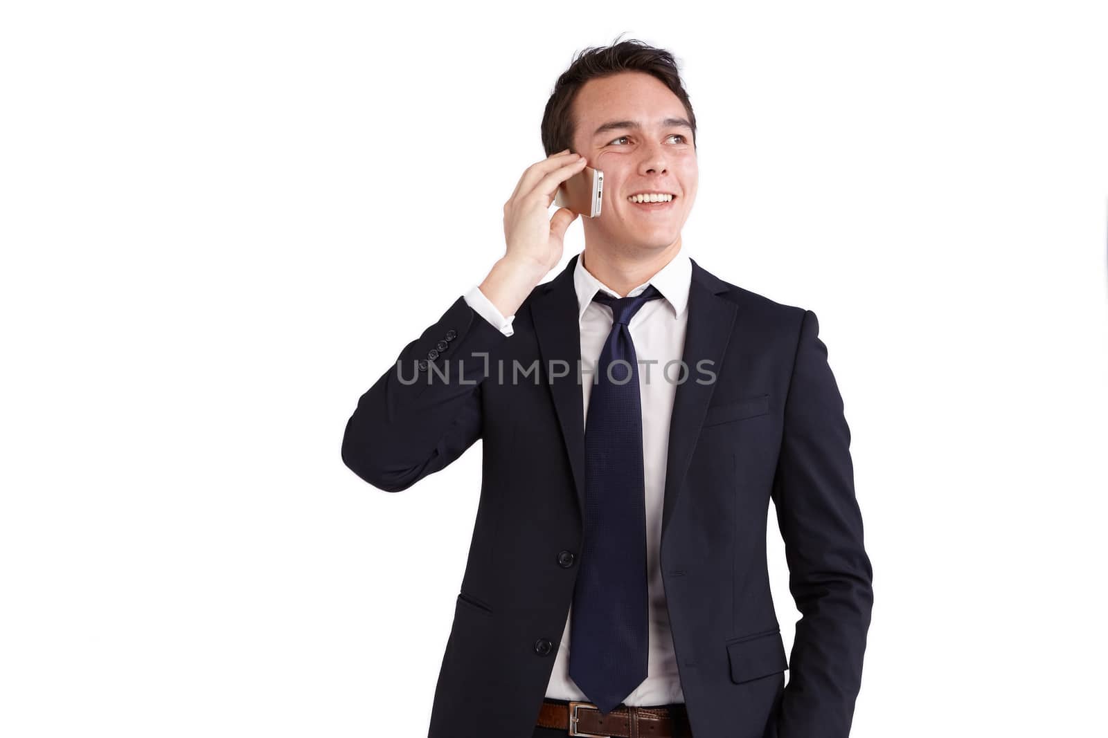 A young caucasian male businessman smiling holding a mobile phone looking away from camera.