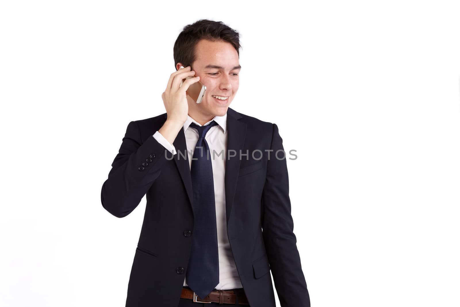 A young caucasian male businessman smiling holding a mobile phone looking away from camera.