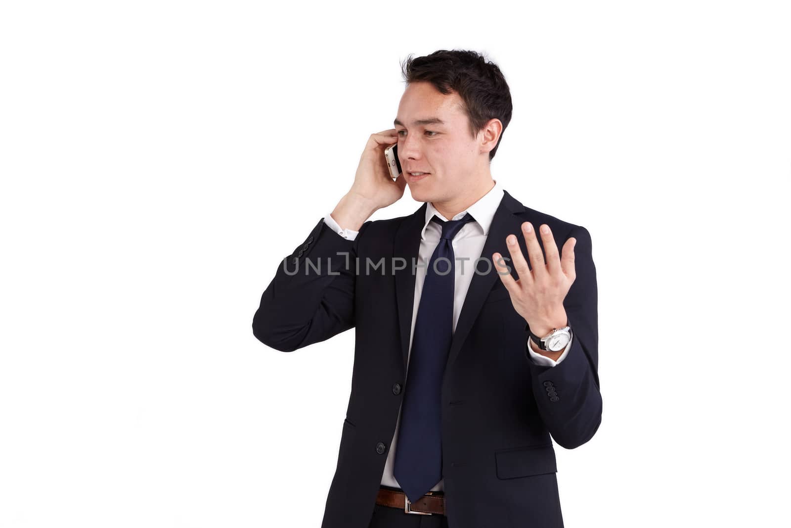 A young caucasian male businessman smiling holding a mobile phone raising his hand looking away from camera.