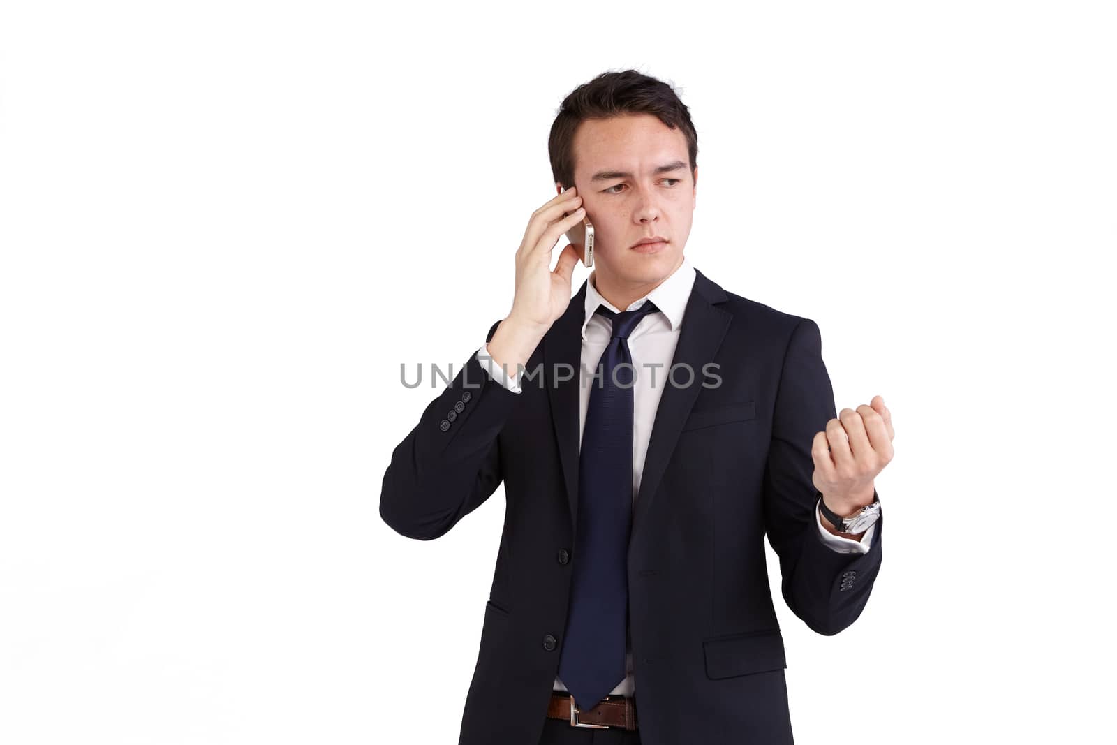 A young caucasian male businessman frowns with raised hand while holding a mobile phone looking away from camera.