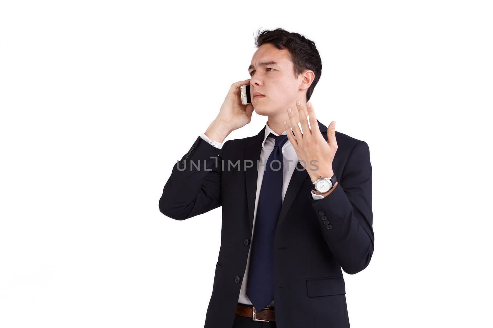 A young caucasian male businessman frowns with raised hand while holding a mobile phone looking away from camera.