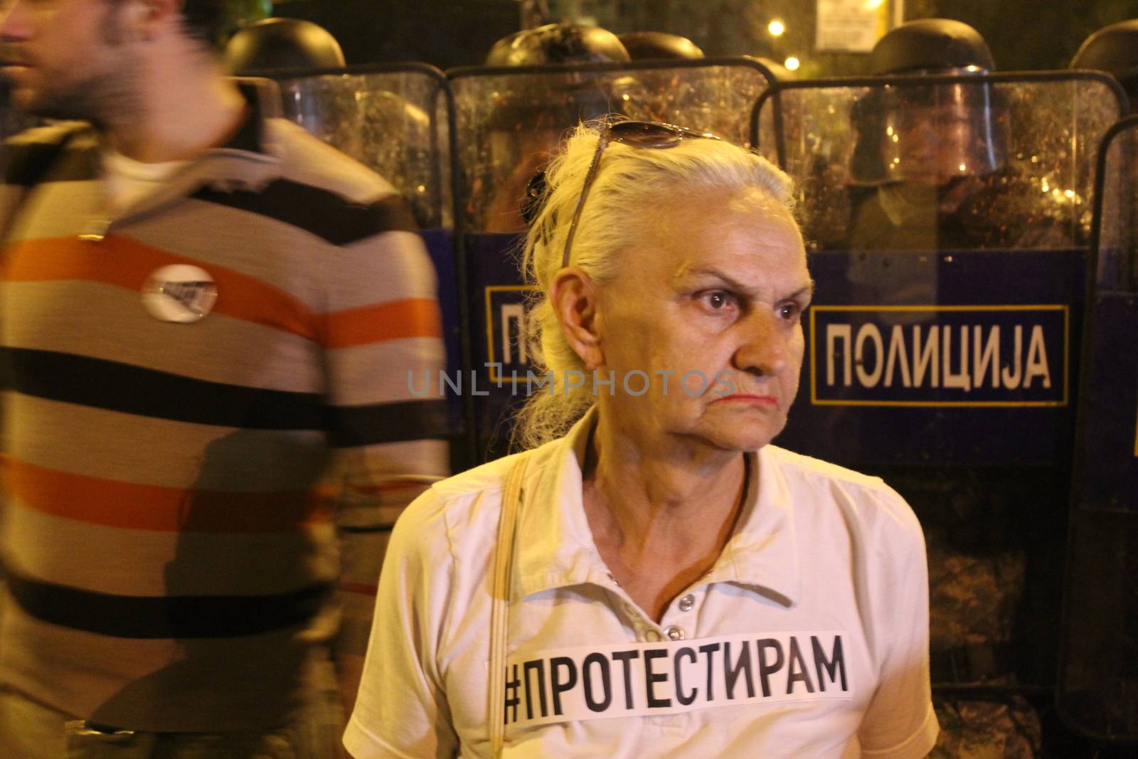 MACEDONIA, Skopje: A woman holds a placard which reads #protest, close to riot police officers, as thousands took to the streets of the Macedonian capital for a third consecutive evening to protest against the president's surprising decision to halt probes into more than 50 public figures embroiled in a wiretapping scandal in Skopje, on April 14, 2016. Similar anti-government protests in the capital had turned violent on Wednesday, when demonstrators ransacked the offices used by President Gjorge Ivanov, and set fire to the furniture.