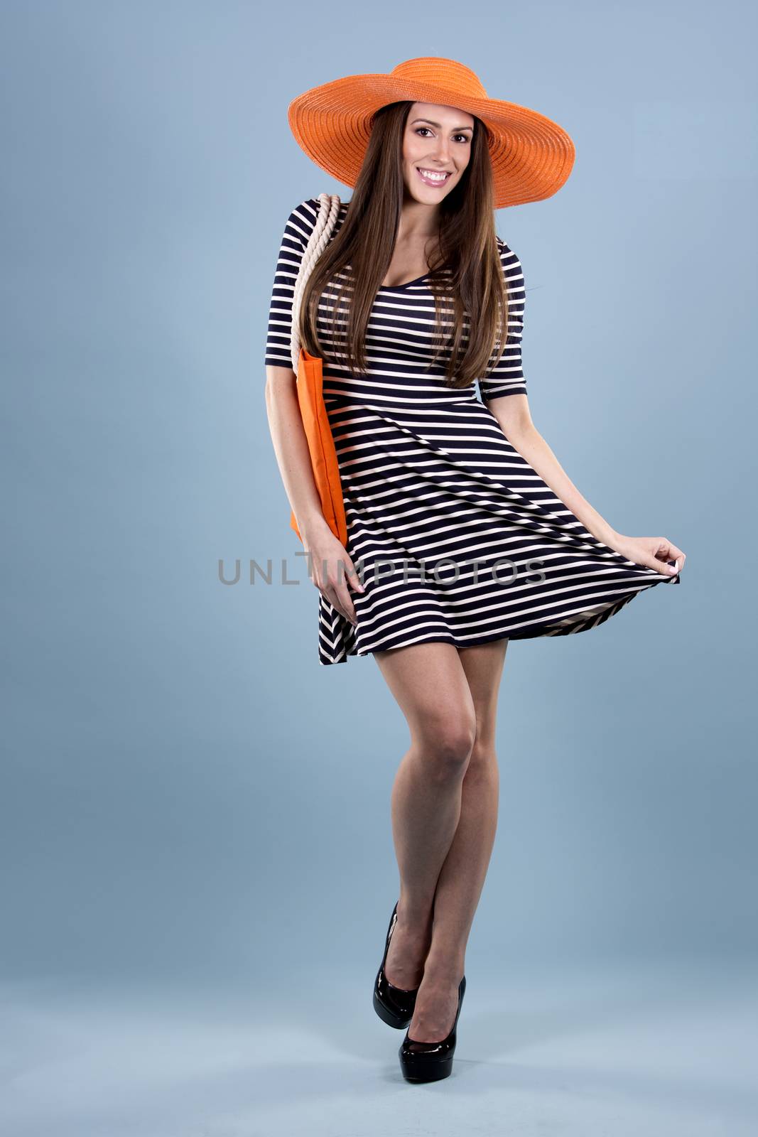 young woman wearing dress and orange hat on blue background