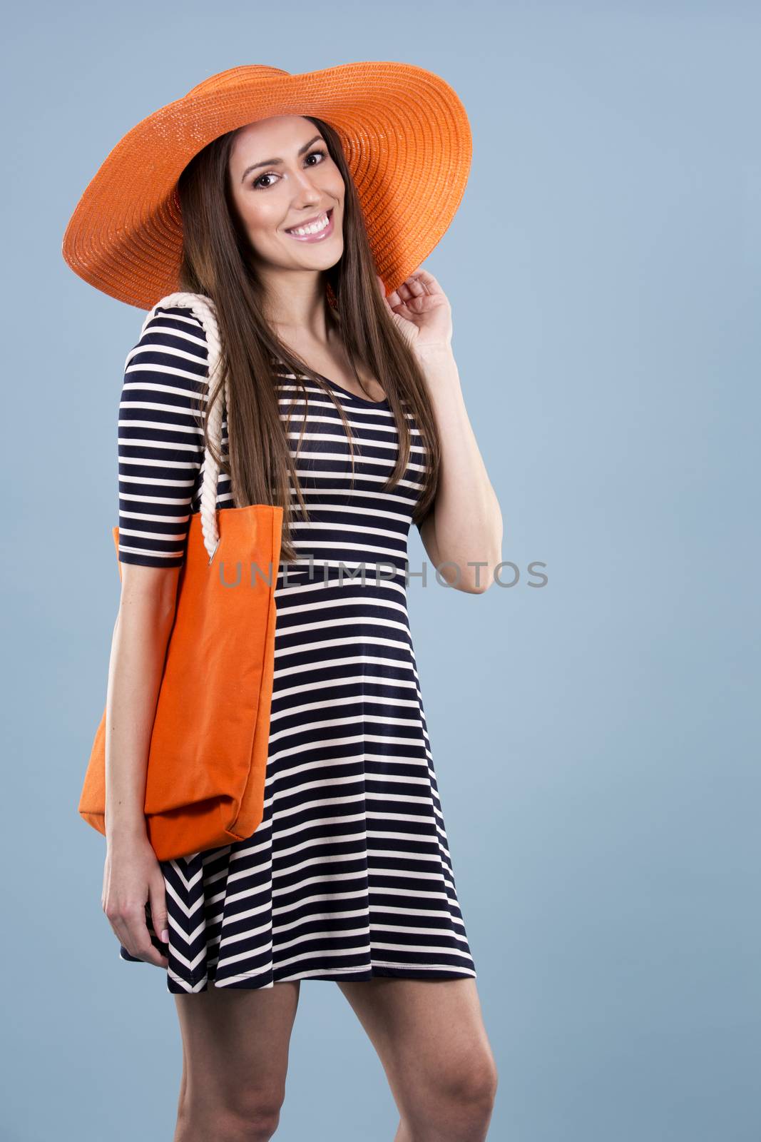 young woman wearing dress and orange hat on blue background