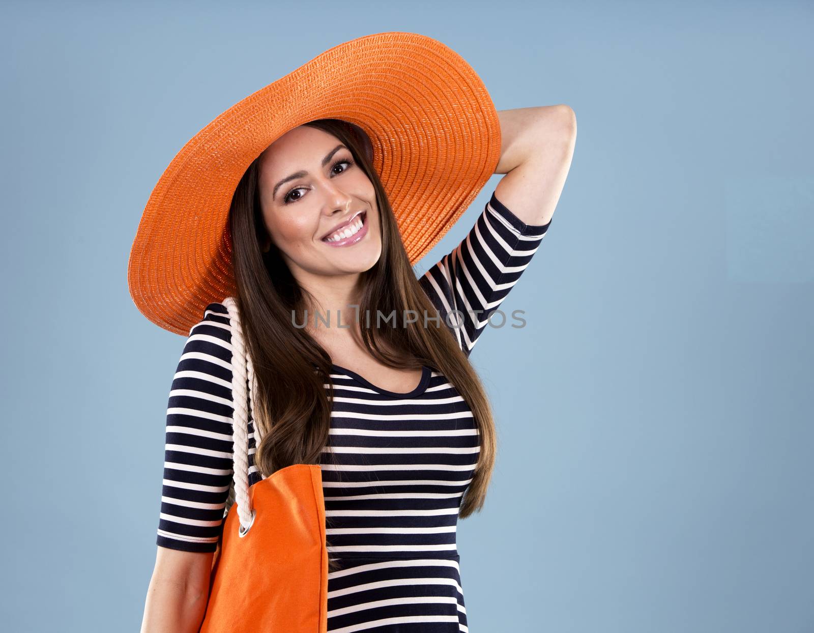 young woman wearing dress and orange hat on blue background