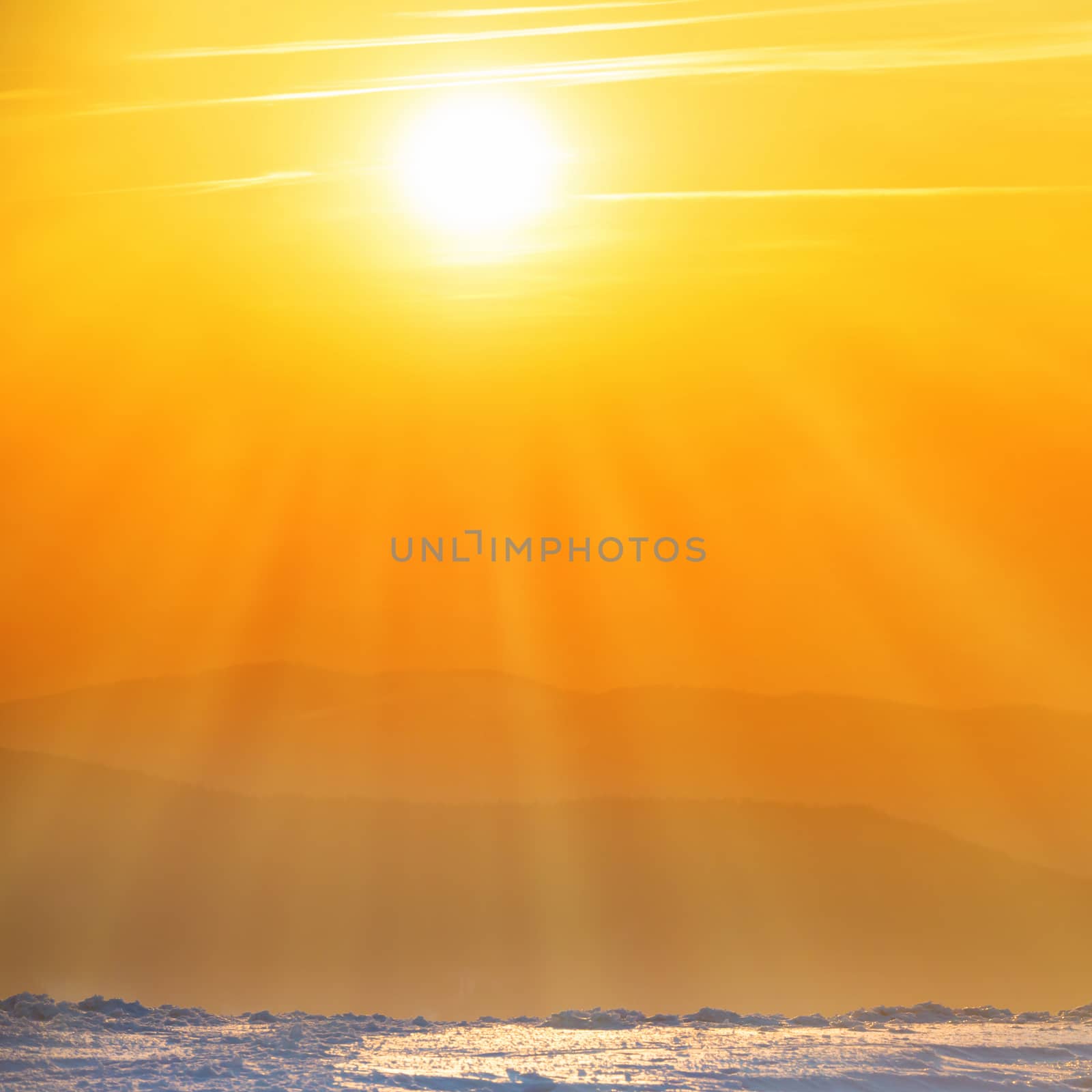 Orange sunset with big sun and sunrays over winter mountains