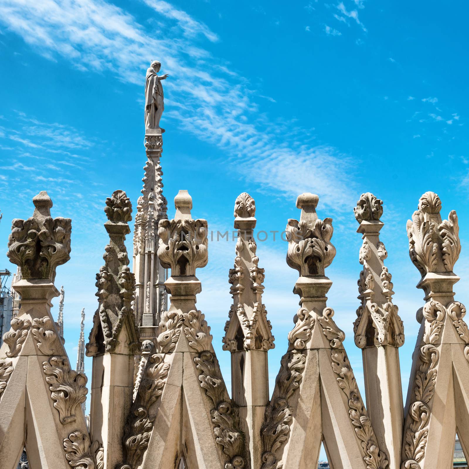 White marble statues on the roof of famous Cathedral Duomo di Milano on piazza in Milan, Italy