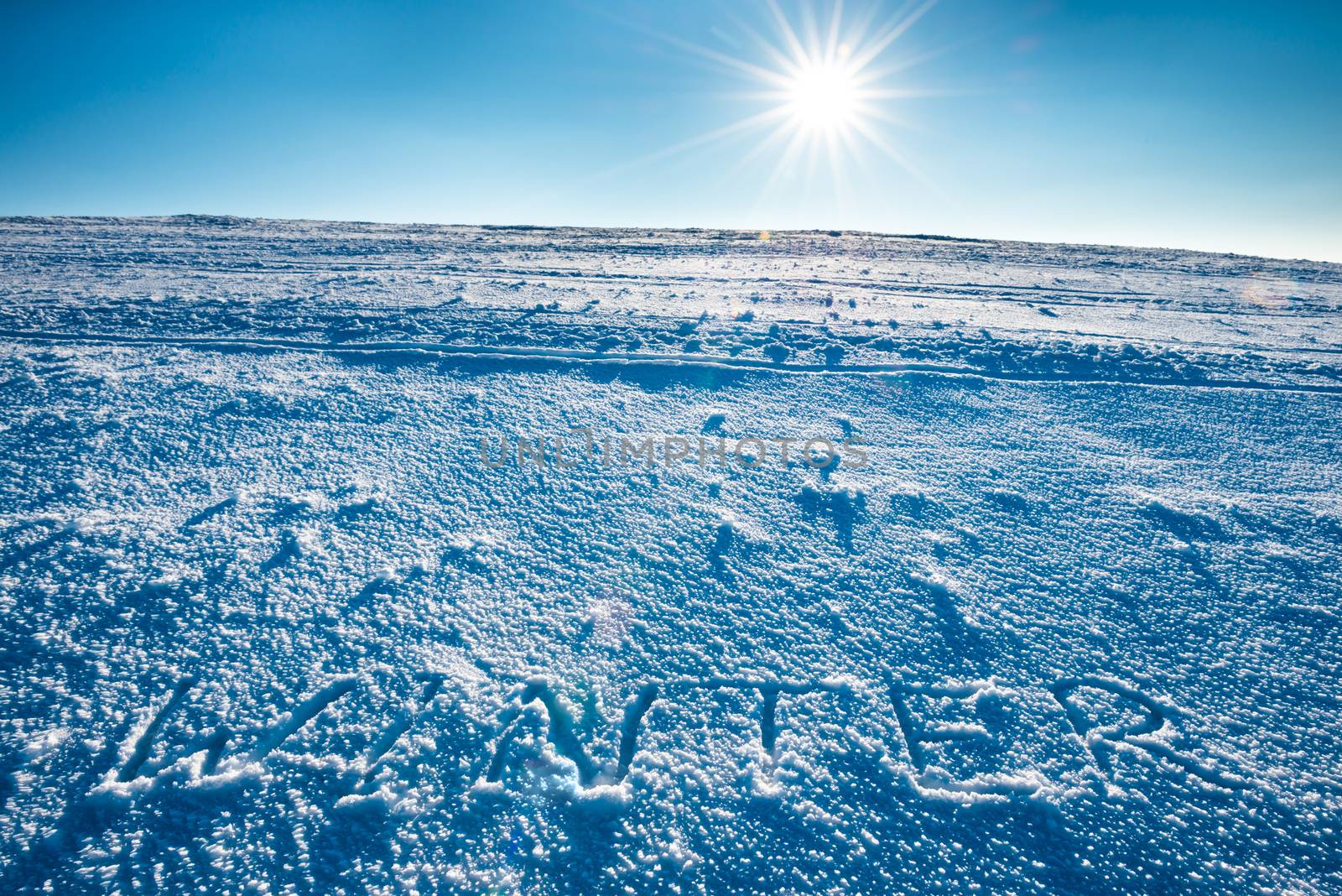 Mountain landscape with word "winter" on the snow over shining sun on bright blue sky