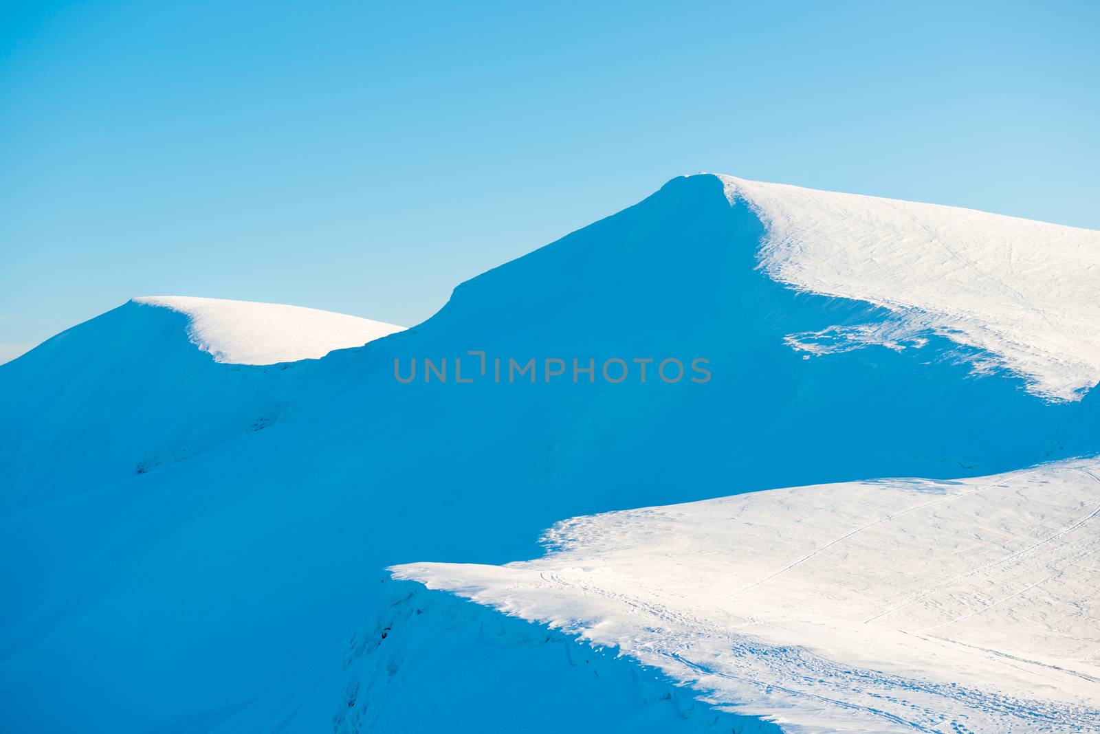 Winter mountains landscape with shining sun on bright blue sky