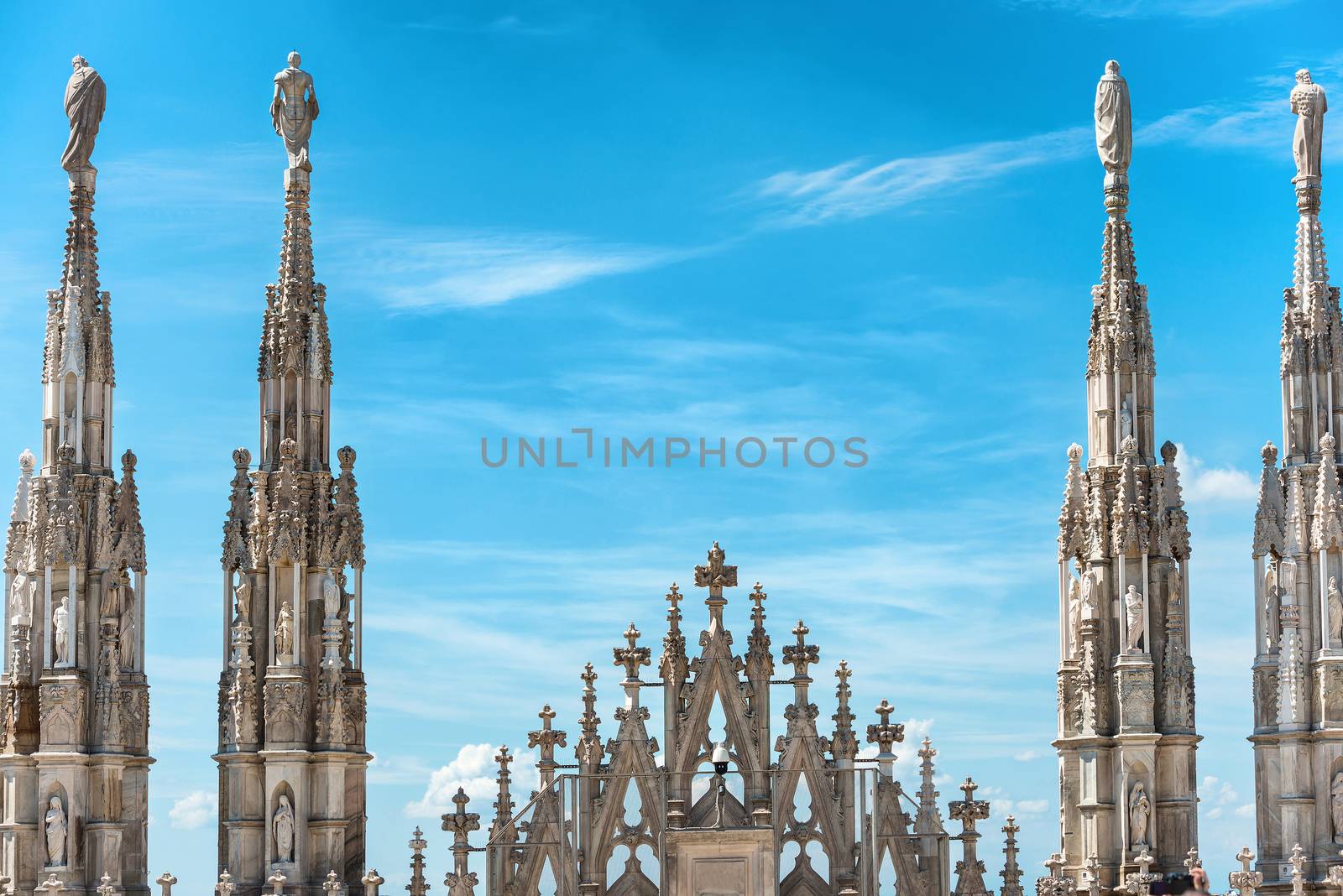 White marble statues on the roof of famous Cathedral Duomo di Milano on piazza in Milan, Italy