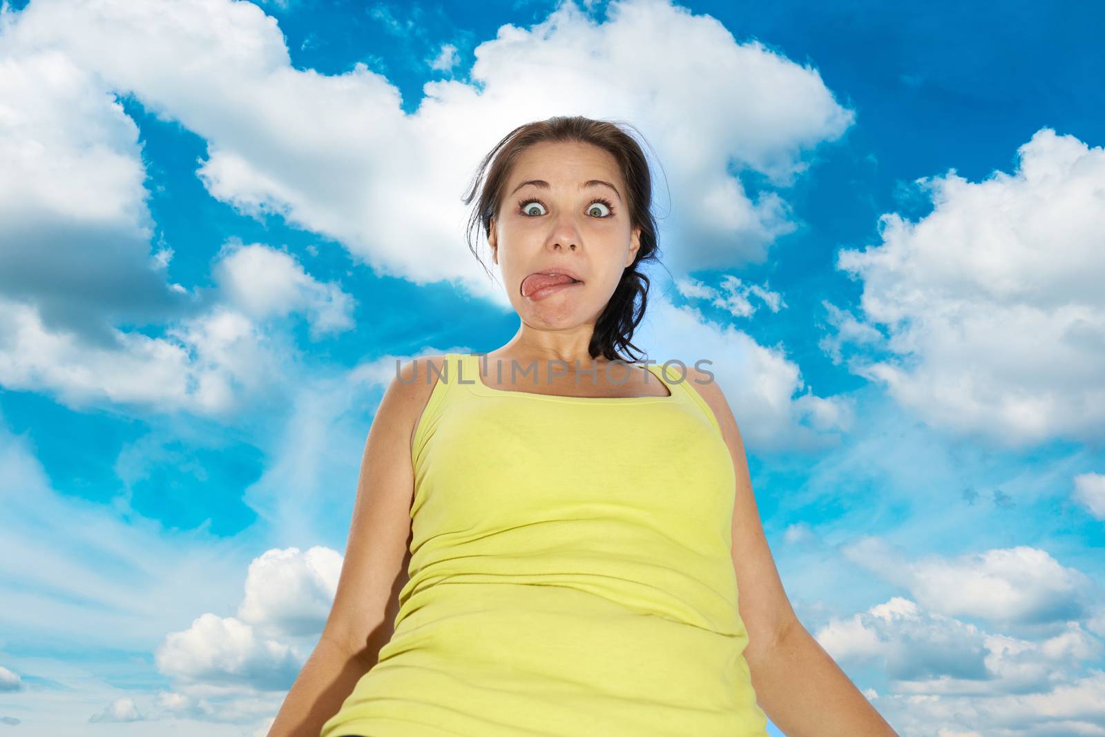Pretty young girl with funny face expression over blue sky with clouds