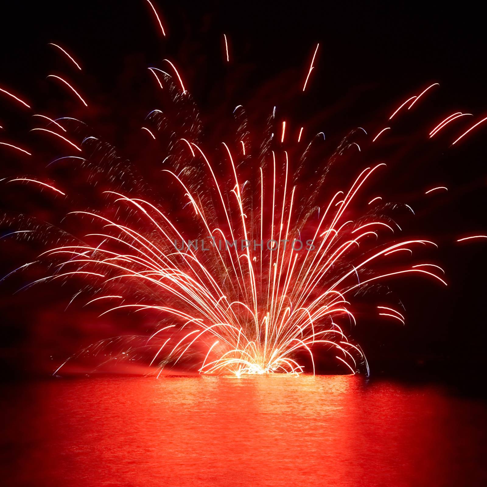 Red holiday fireworks on the lake with black sky background