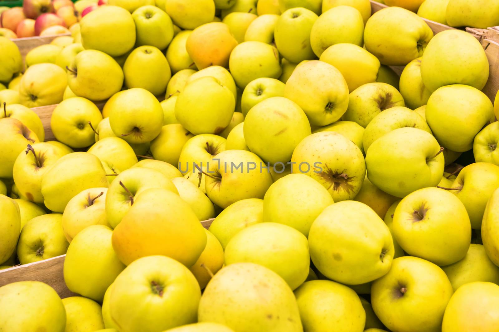 Pile of yellow fresh apples in a wooden crates at farmers market