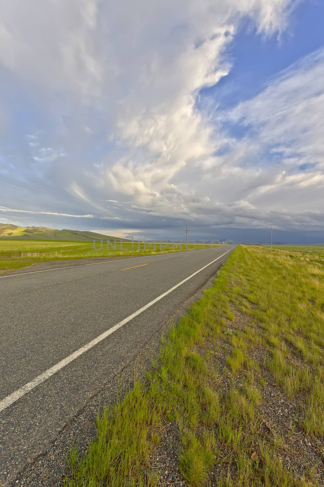 A thunderstorm building up in the distance over a deserted road in Montana.