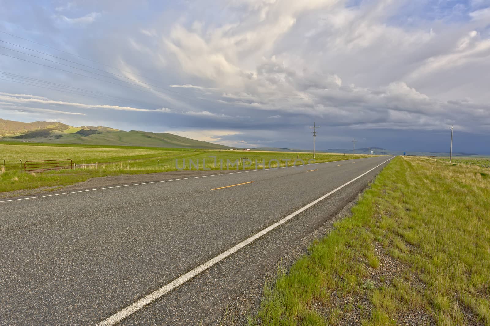 A thunderstorm building up in the distance over a deserted road in Montana.