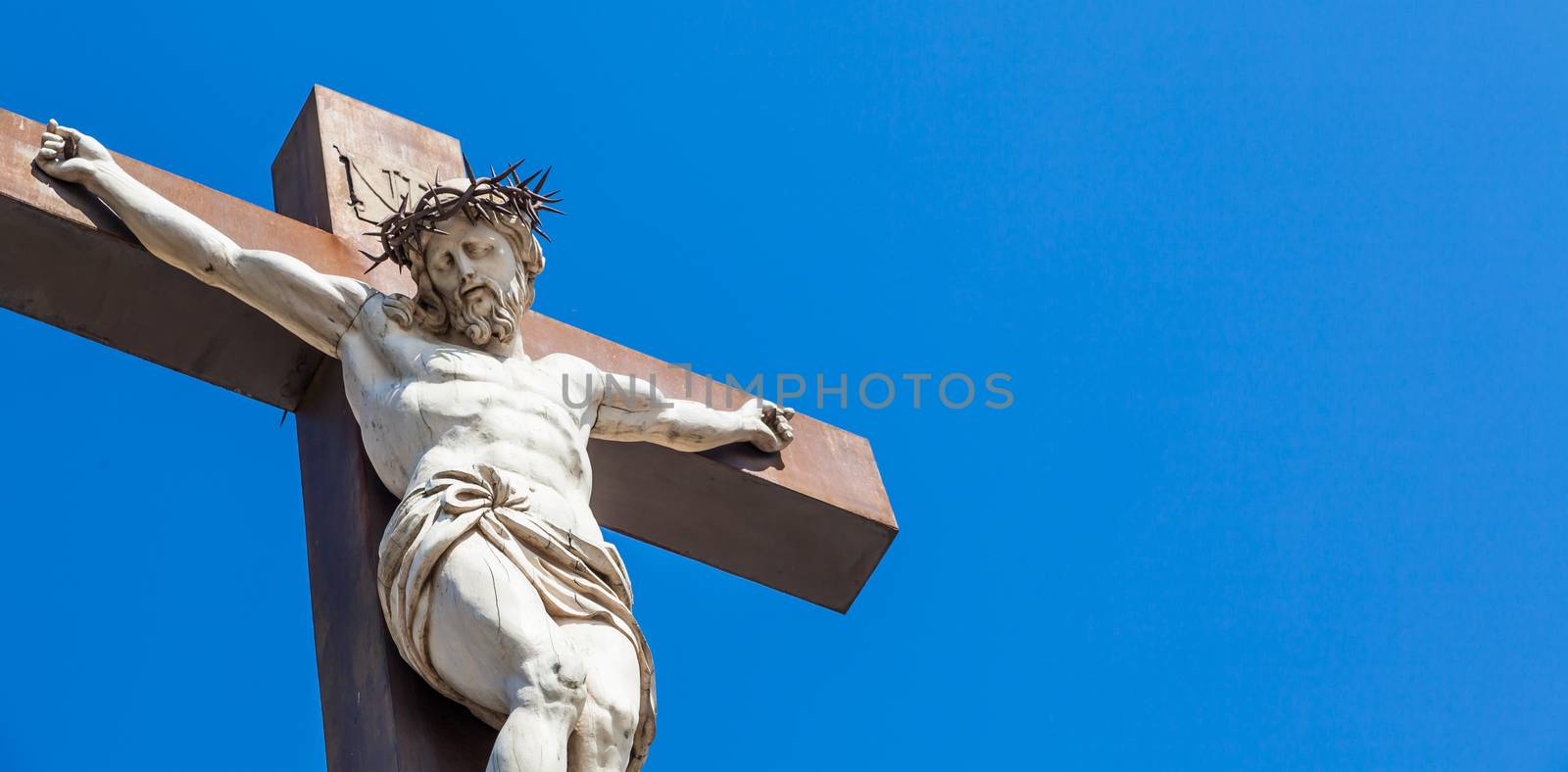 Crucifix made of marble with blue sky in background. France, Provence Region.