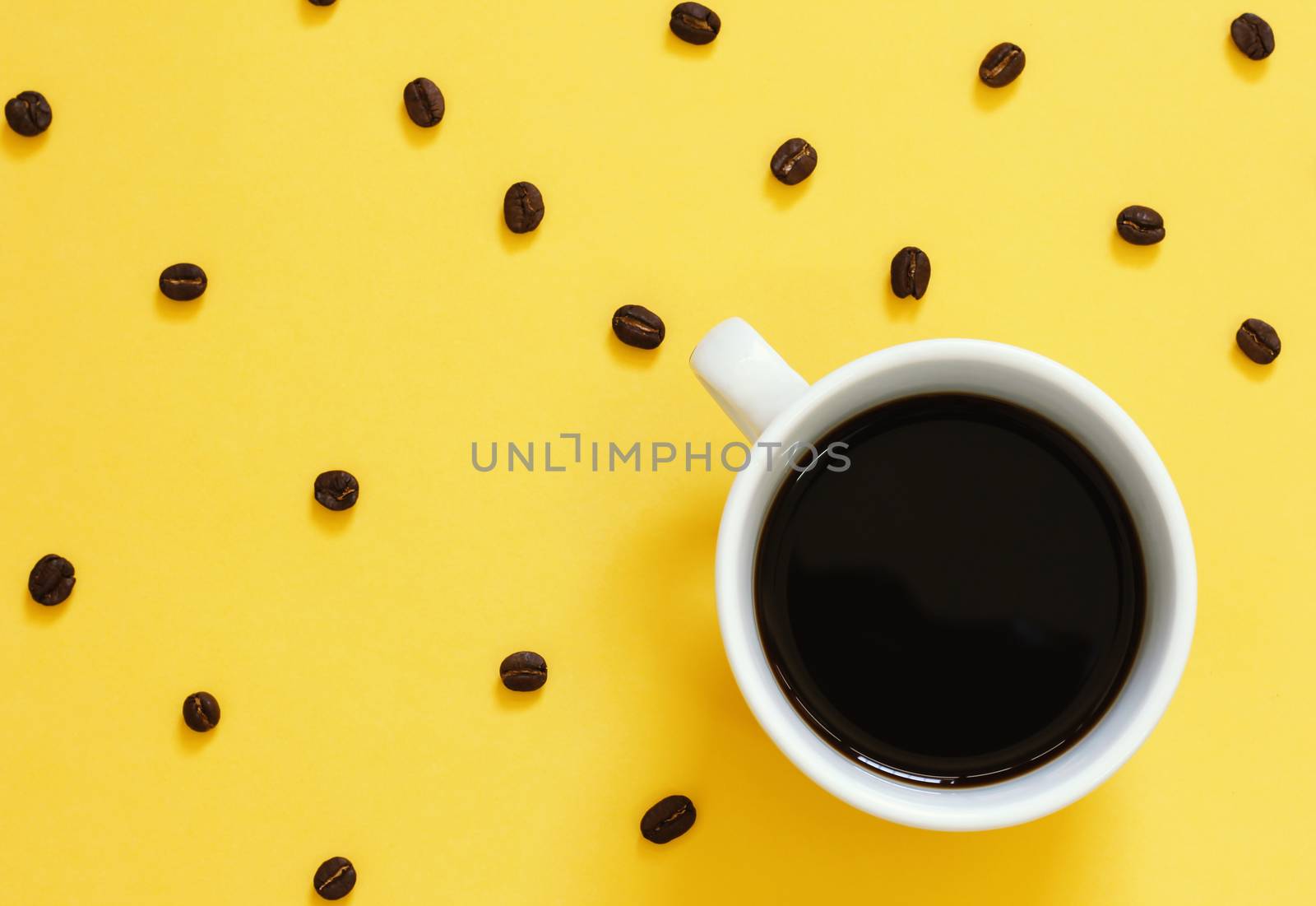 Top view of black coffee and coffee beans on yellow background