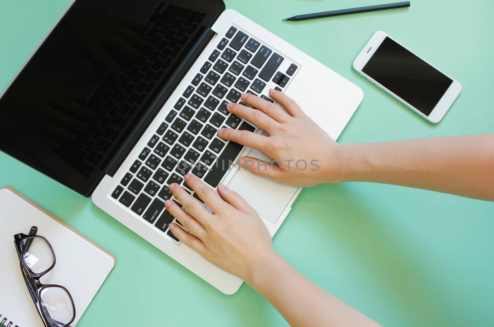 Hand using laptop on creative flat lay workspace desk with smart by nuchylee