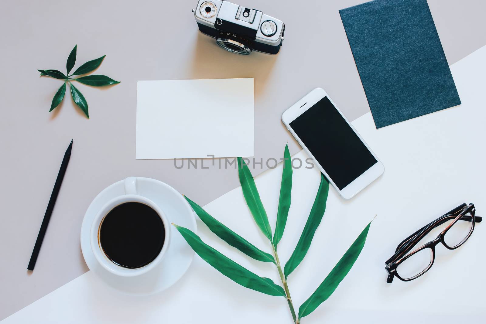 Creative flat lay photo of workspace desk with smartphone, coffee, film camera, blank paper and envelope with copy space background, minimal style
