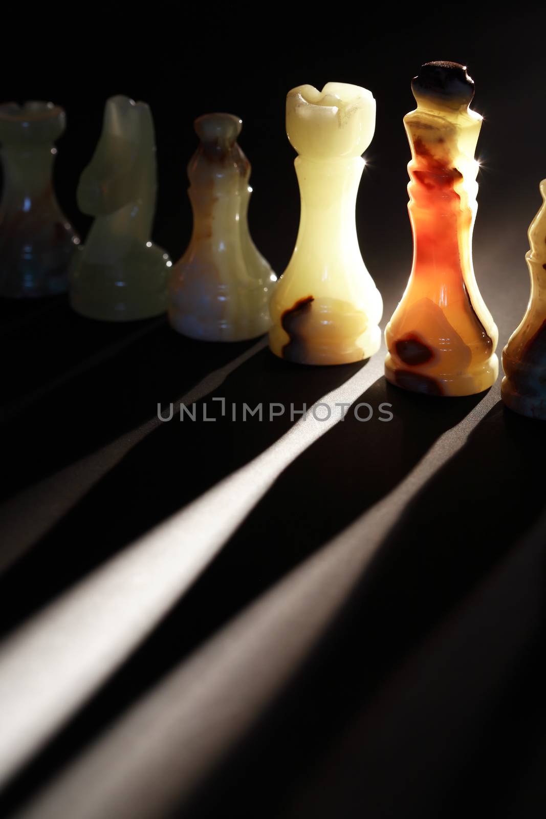 Set of chess pieces made from onyx against light on dark background
