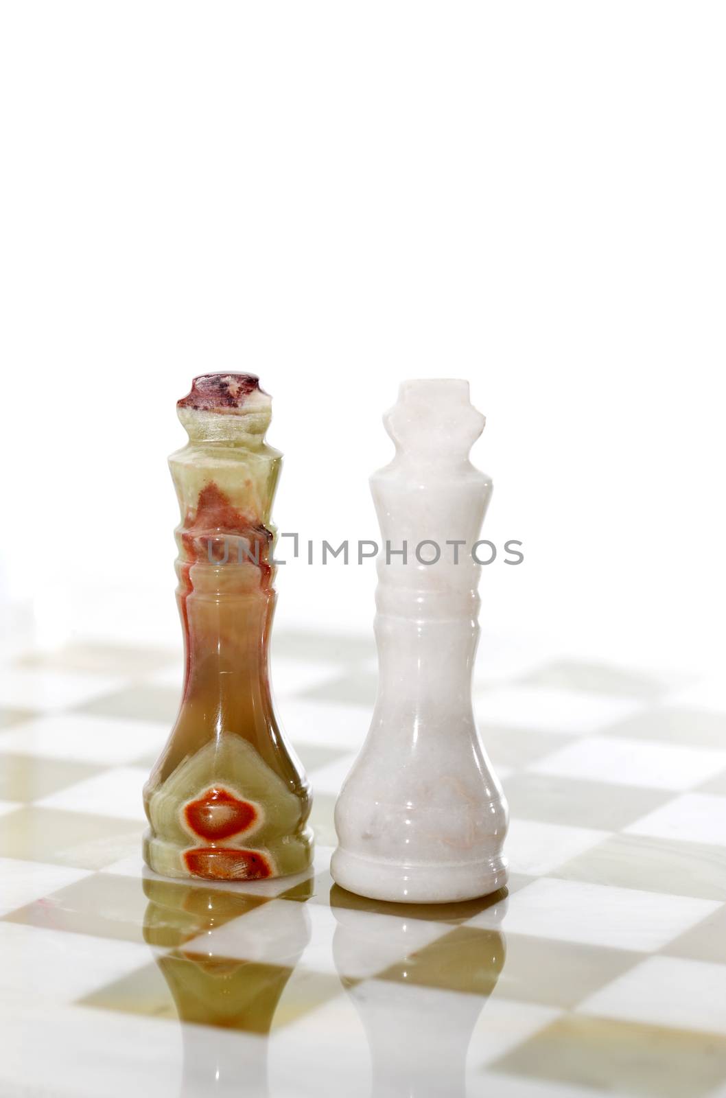 Pair of chess Kings made from Onyx on board against white background