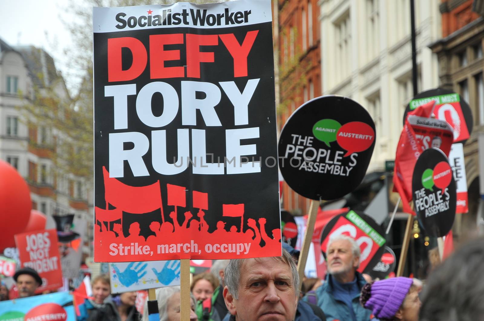 UNITED KINGDOM, London: A protester holds a sign reading 'Defy Tory Rule' as ten of thousands march and protest against the Tories government and demanded David Cameron's resignation in Trafalgar square in London on April 16, 2016. Protesters descended to London in hundreds of coaches from all over the UK to take part in this anti-austerity protest.