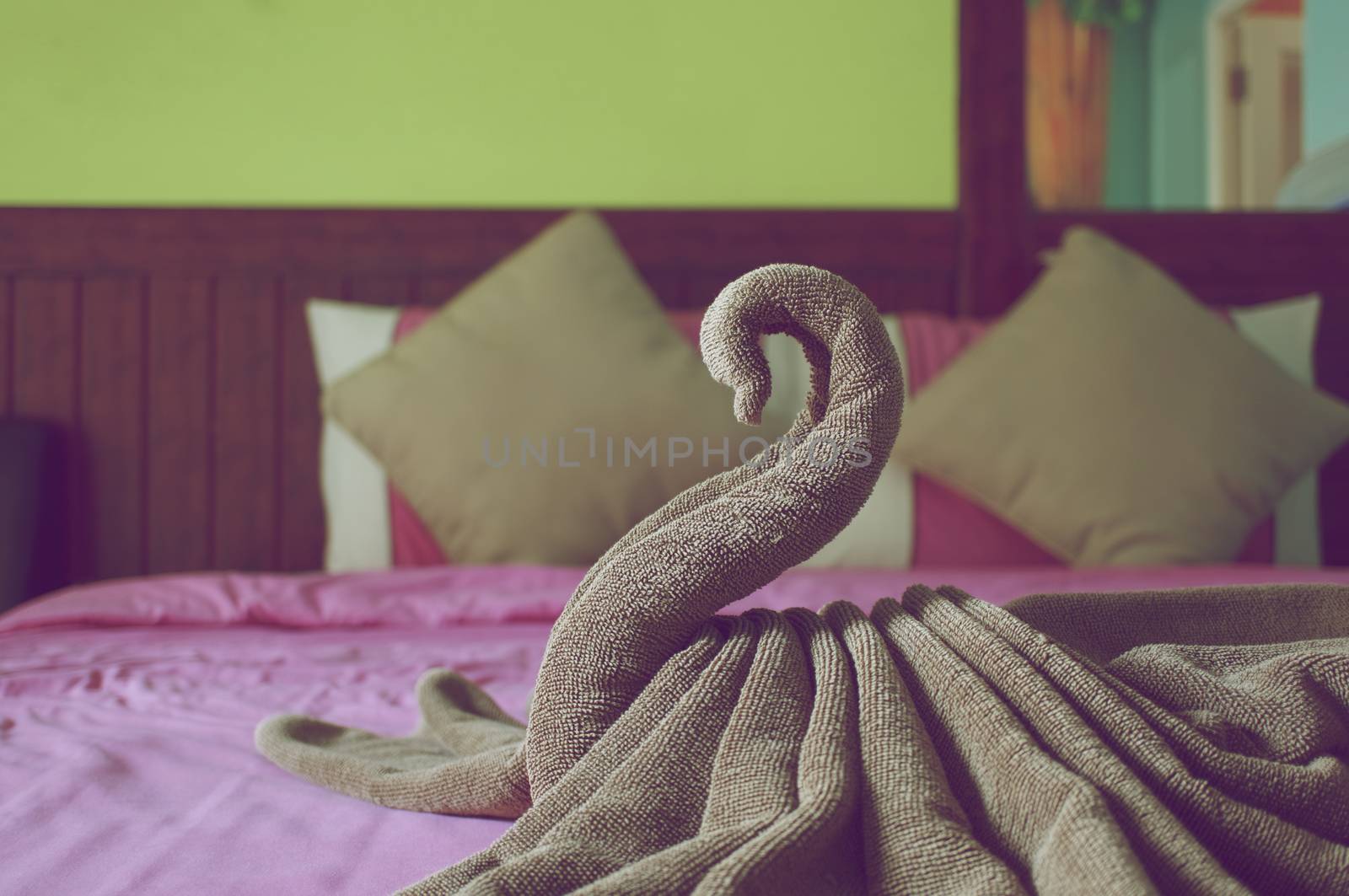 Brown towel plait as swan on bed in hotel room vintage style.